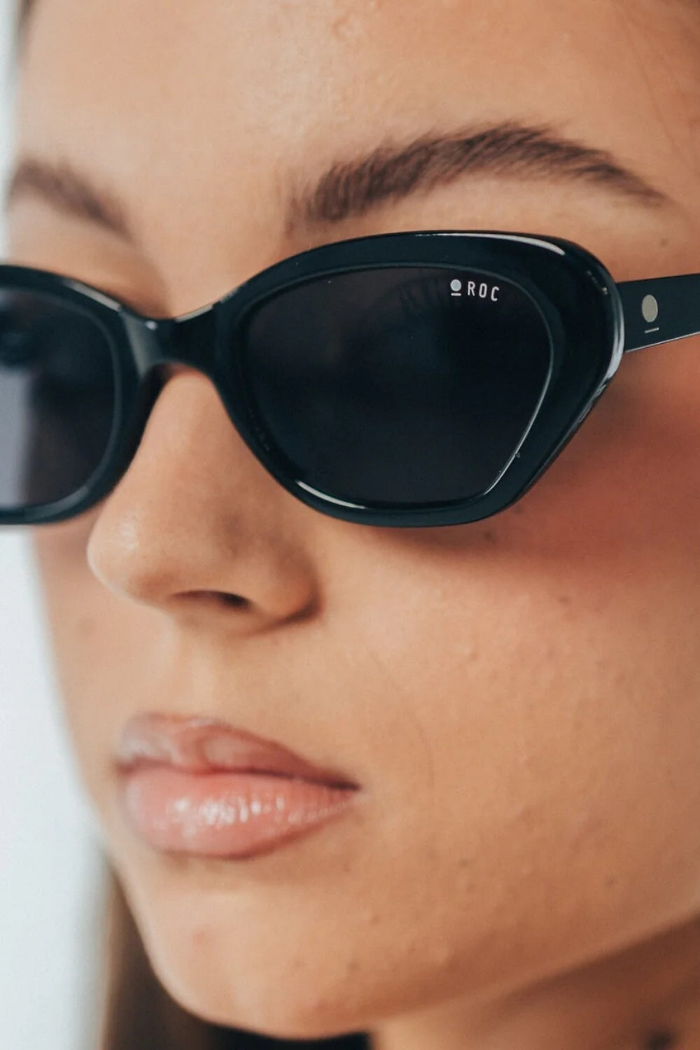 Close-up of a person wearing black sunglasses with 'ROC' branding.