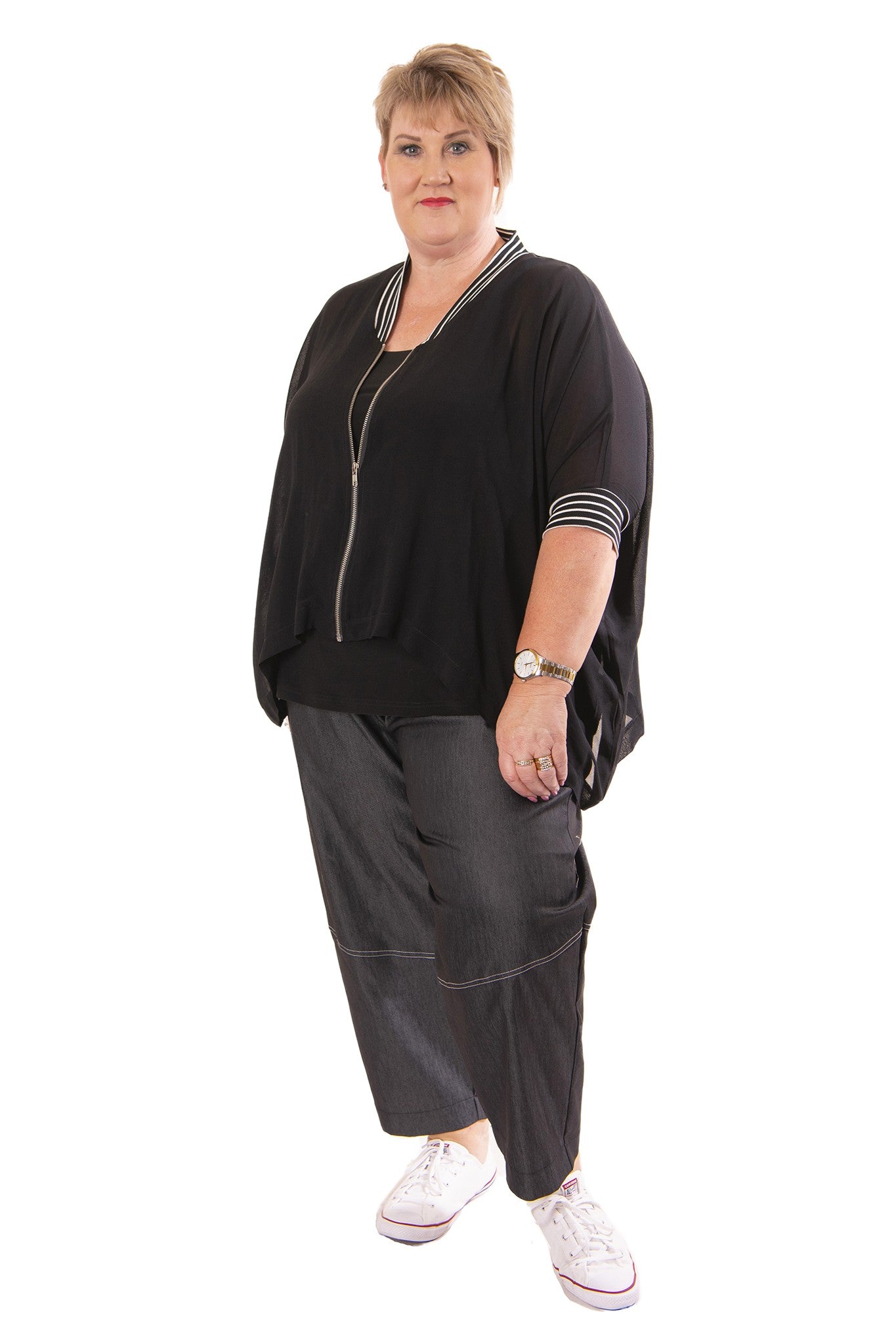 Woman wearing a black outfit with white sneakers on a white background