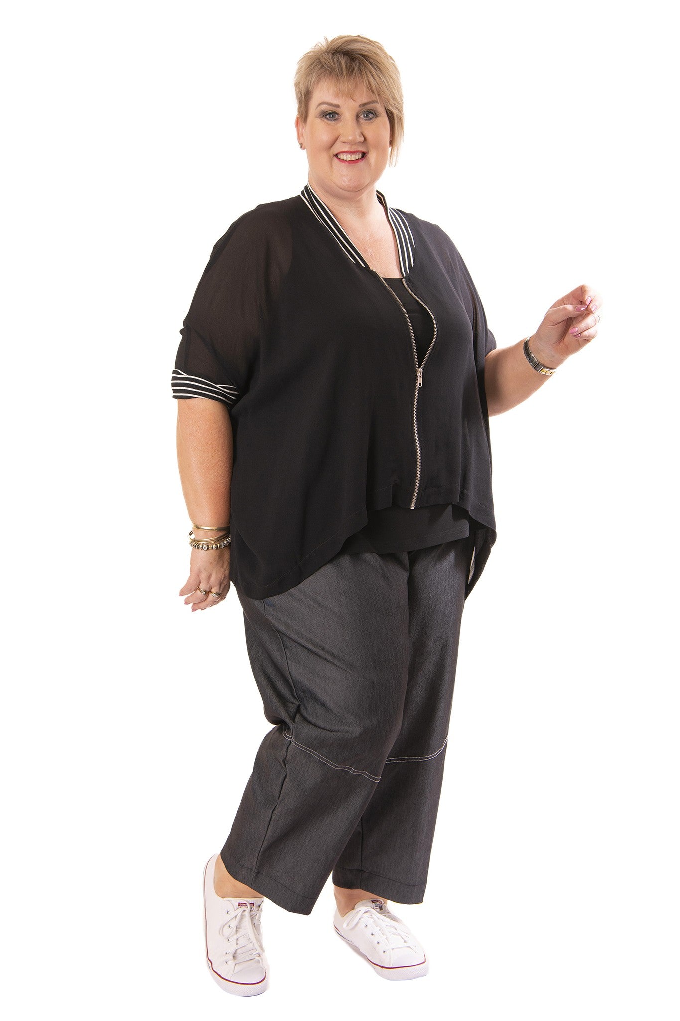 Woman wearing a black top and gray pants on a white background