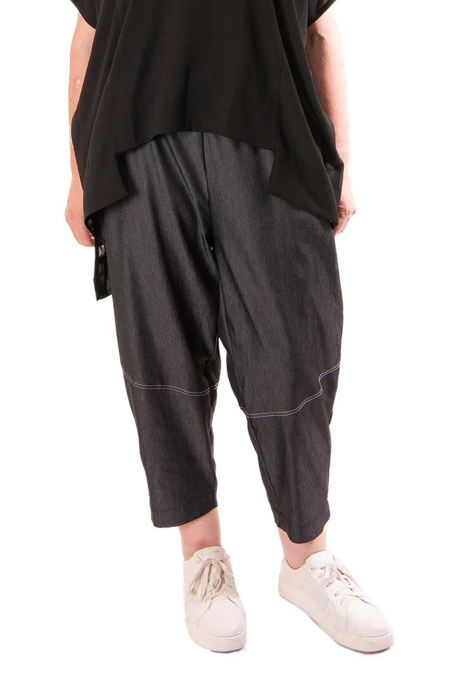 Person wearing black harem pants and a black top on a white background