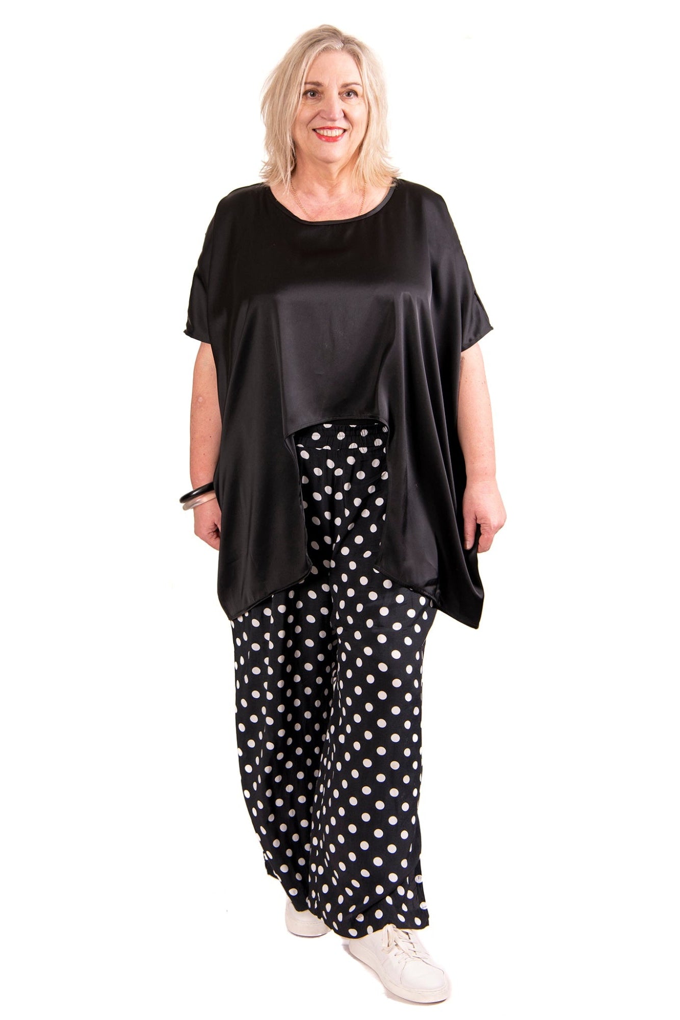 black satin curve hem top and spot pants worn by model against white background