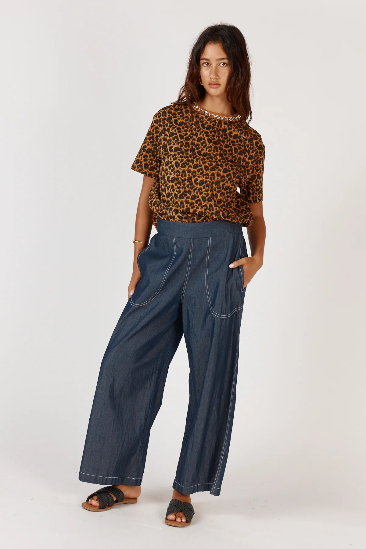 Woman wearing a leopard print top and blue jeans on a white background