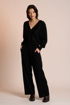 Woman wearing a black outfit against a beige background