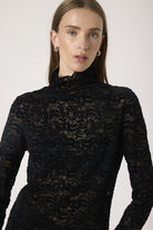 Woman wearing a black lace top against a white background