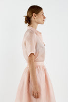 Woman wearing a light pink shirt against a white background