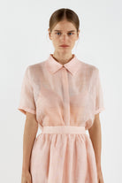 Woman wearing a light pink shirt with a collar on a white background