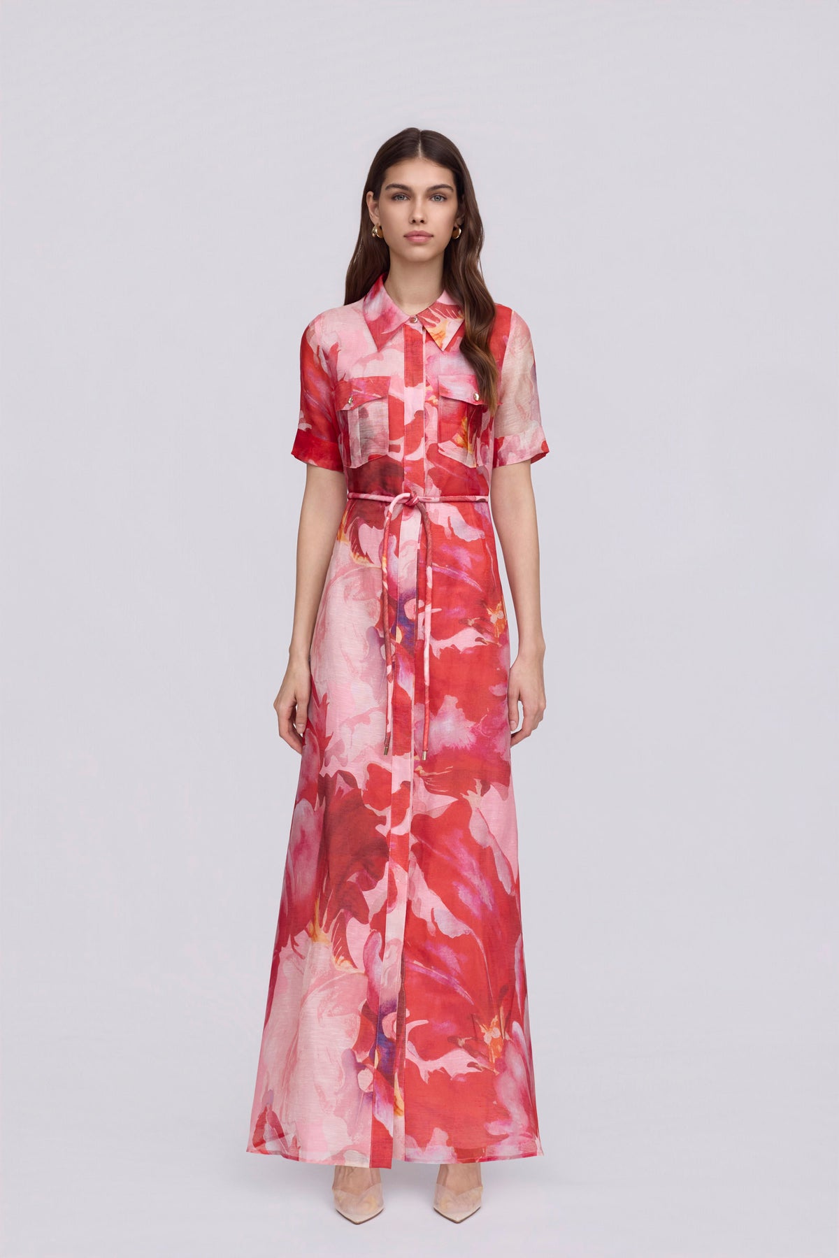 women wearing a pink and red floral maxi dress with a removable waist tie on a plain background