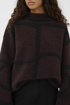 Person wearing a dark burgundy sweater with a white background