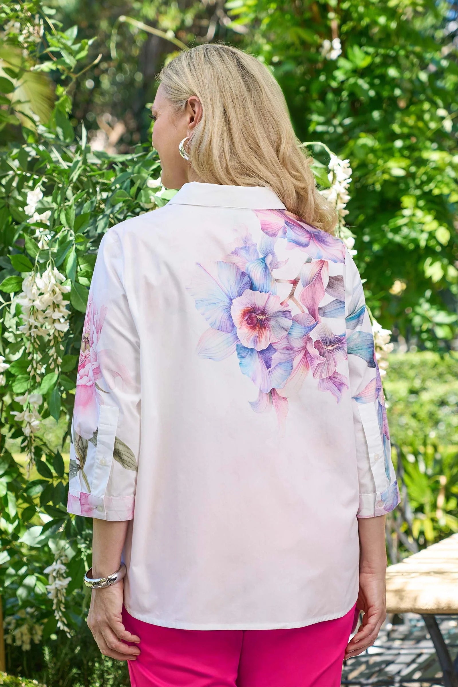 Woman wearing a floral-patterned blouse with a garden background