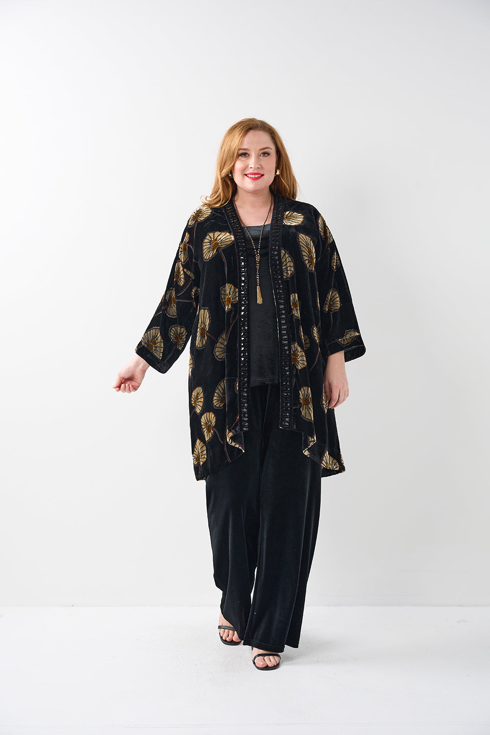 Woman wearing a black outfit with gold patterns on a white background