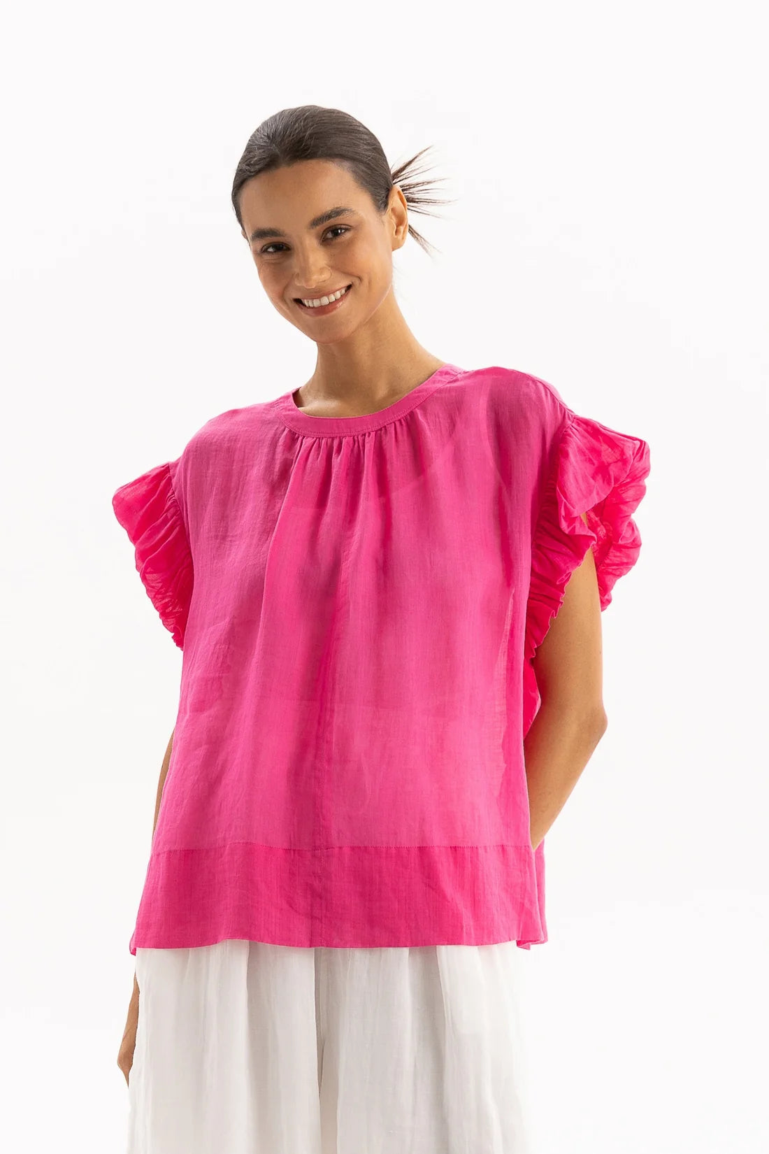 Woman wearing a bright pink blouse with ruffled sleeves on a white background