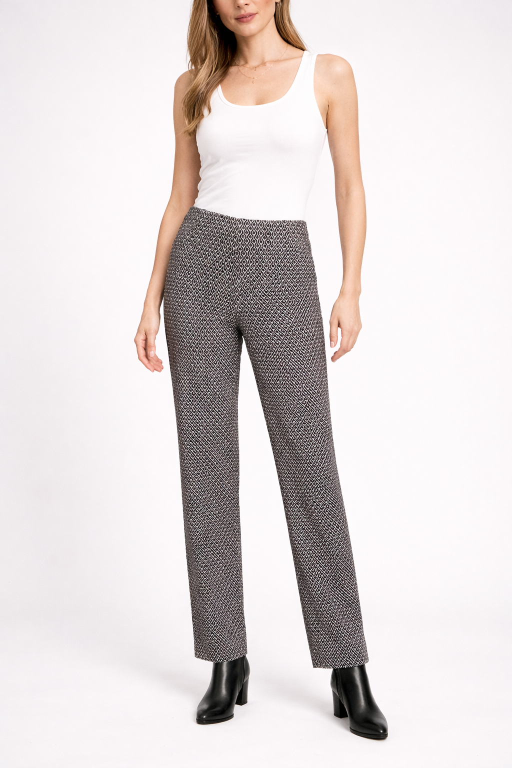 Woman wearing a white sleeveless top and patterned pants on a white background