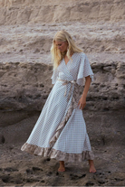 Woman in a long dress standing on rocky terrain with a cliff in the background