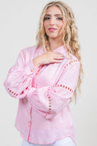 Woman wearing a pink blouse with decorative sleeves on a white background