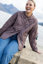 Woman wearing mauve brown quilted bomber in mountain setting