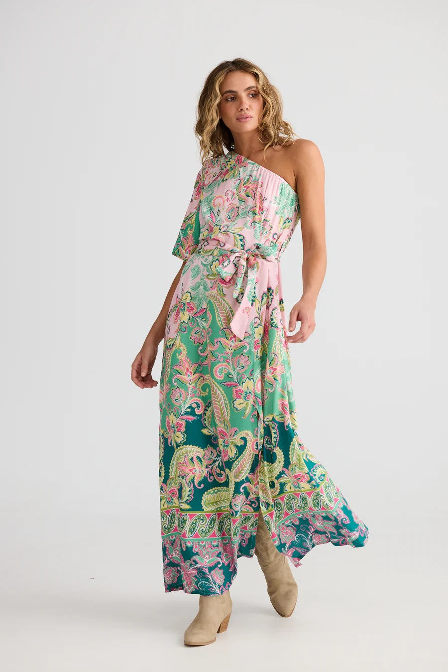 Woman wearing a floral one-shoulder dress with a belt on a white background