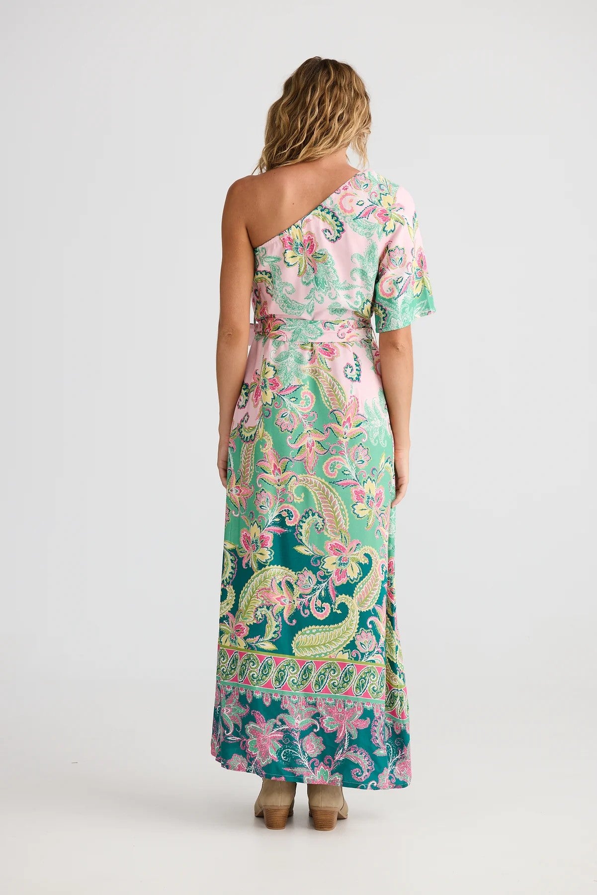 Woman wearing a one-shoulder floral dress on a white background back