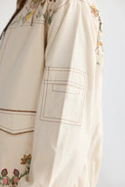 Close-up of a beige fabric with floral embroidery on a light gray background