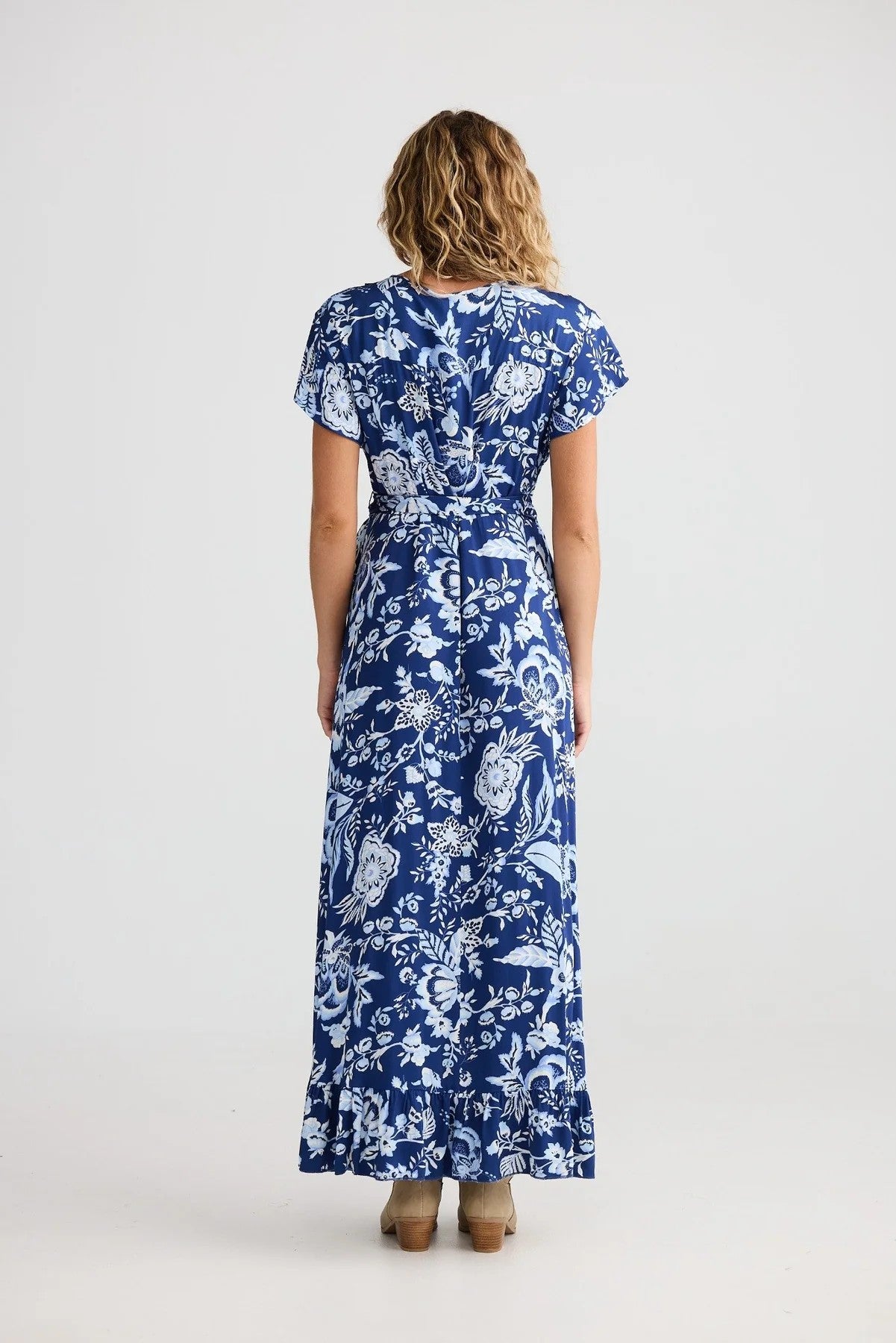 Woman wearing a blue floral dress on a white background back