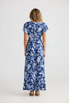 Woman wearing a blue floral dress on a white background back