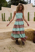 Woman wearing a floral tiered dress standing in front of a desert-like setting with cacti.