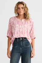 pink cream floral blouse and jeans worn by model 