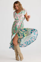 Woman wearing a colorful floral dress with beige knee-high boots on a white background