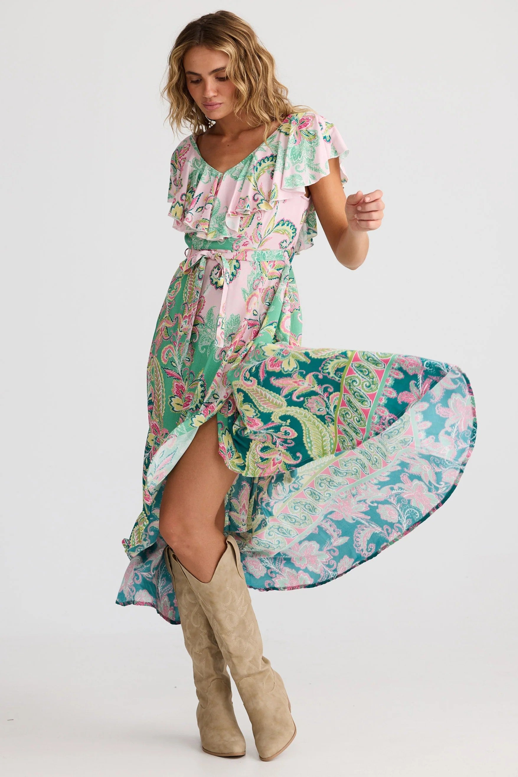 Woman wearing a colorful floral dress with beige knee-high boots on a white background
