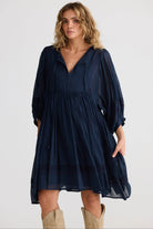 Woman wearing a navy blue dress with long sleeves on a white background