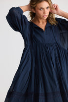 Woman wearing a navy blue dress against a plain background