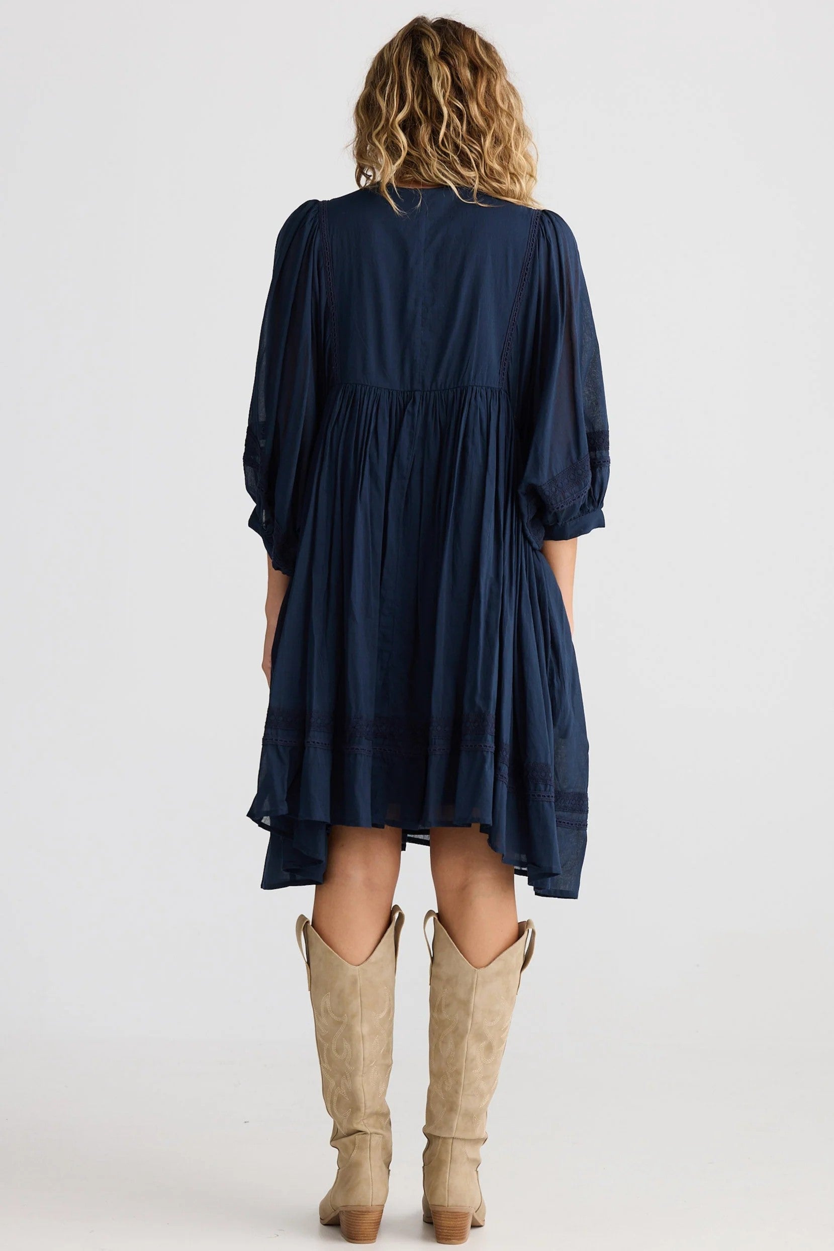 Person wearing a navy dress with long sleeves and a white background back