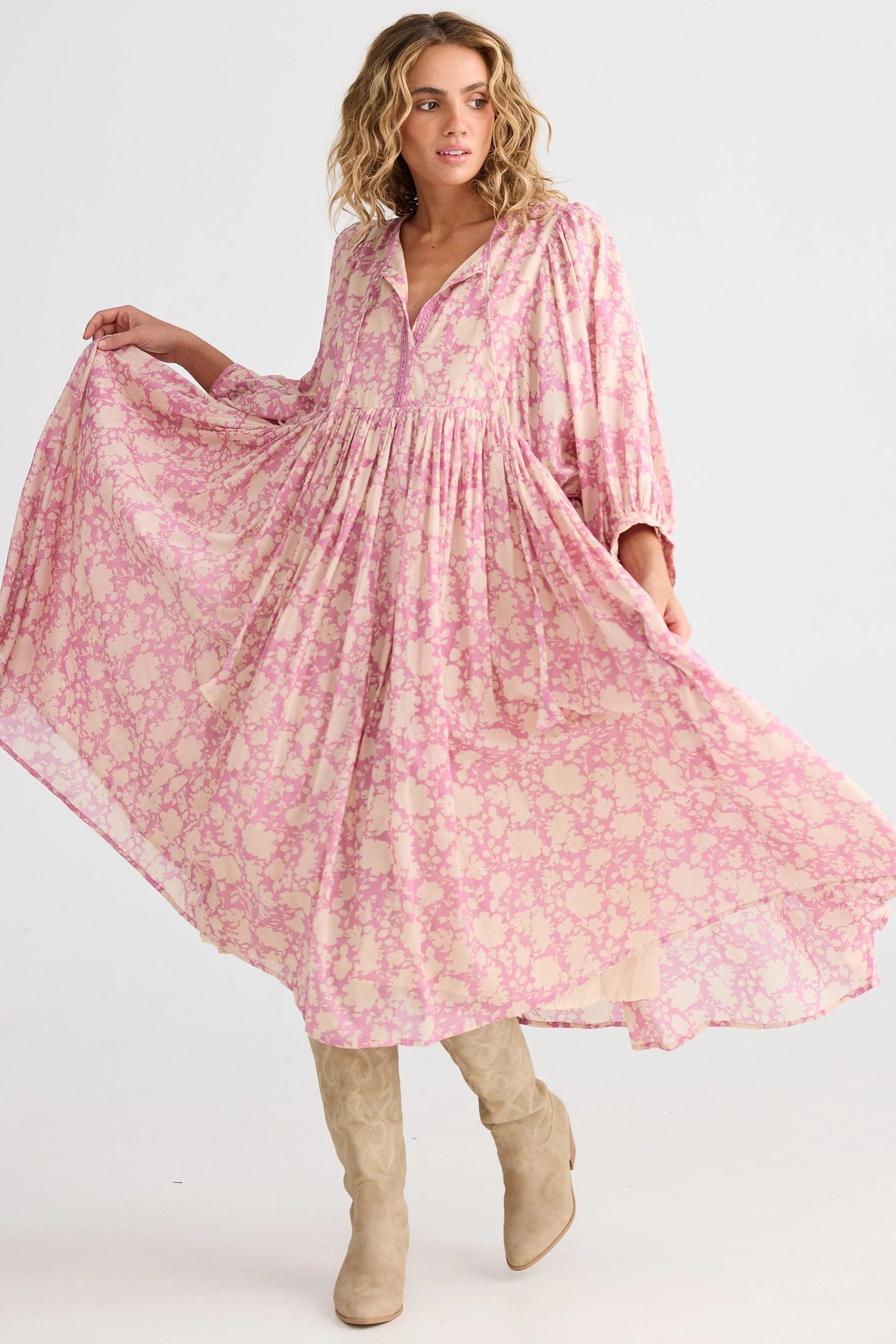 Woman wearing a pink floral dress with long sleeves on a white background