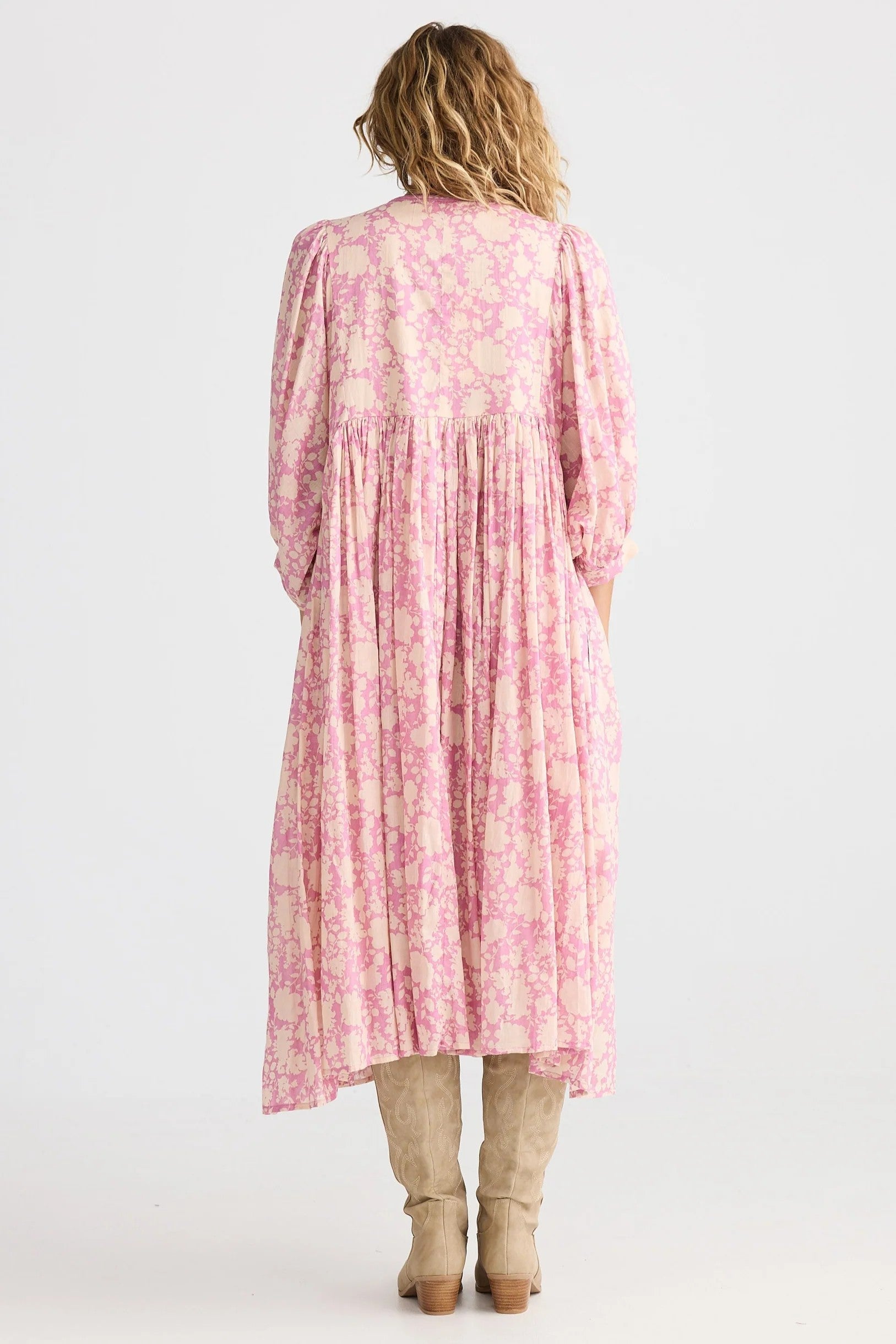 Woman wearing a pink floral dress with a white background