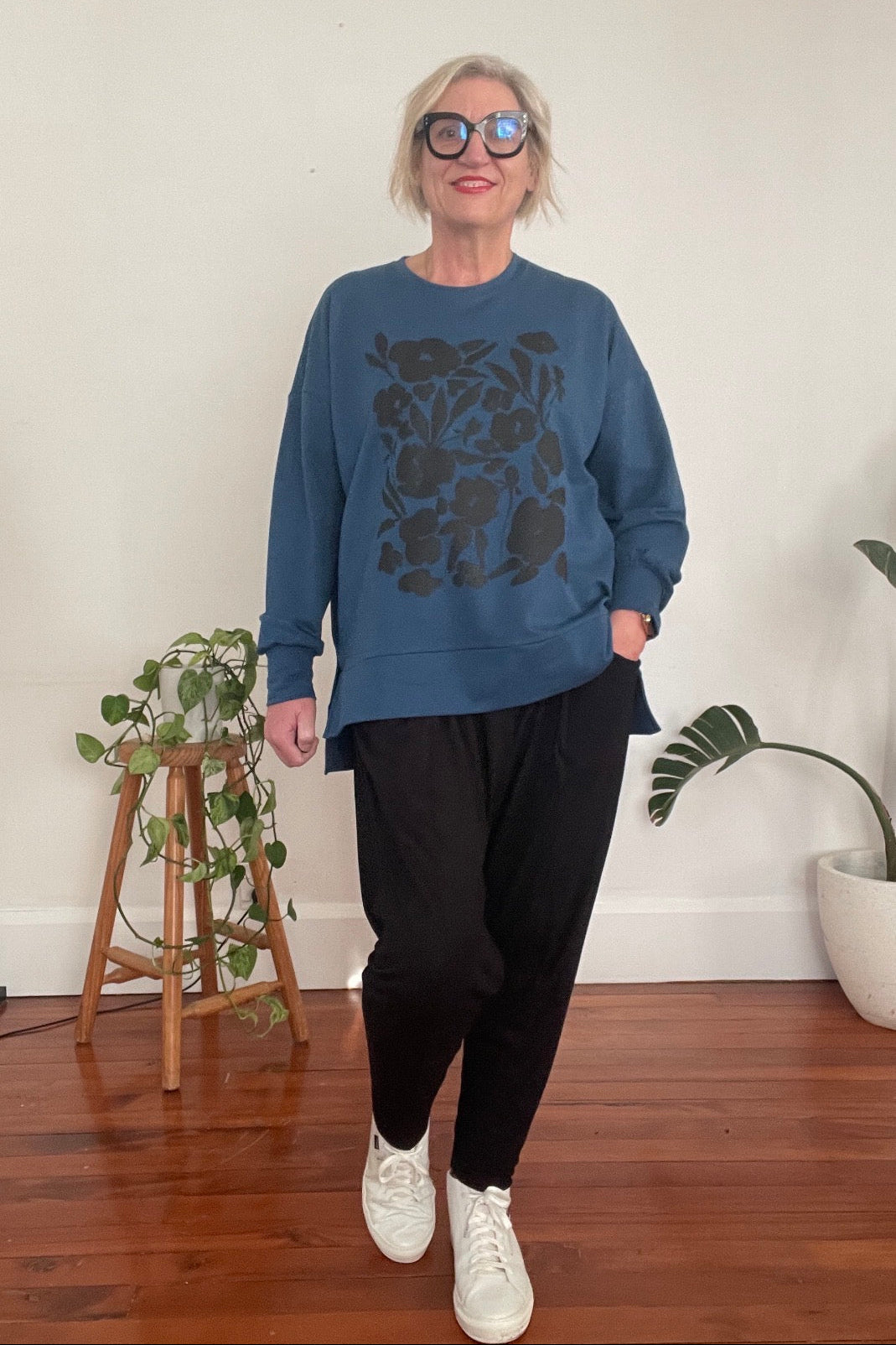 Person wearing a blue sweatshirt with floral design indoors
