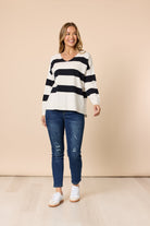Woman wearing a striped sweater and jeans against a beige background