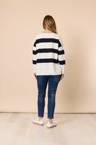 Person wearing a striped sweater and jeans against a beige background