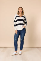 Woman wearing a striped sweater and jeans against a beige background