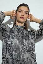 Woman wearing a black and white patterned dress and black boots on a white background close up