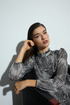 Woman wearing a black and white patterned dress and black boots on a white background