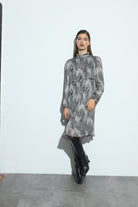 Woman wearing a black and white patterned dress and black boots on a white background