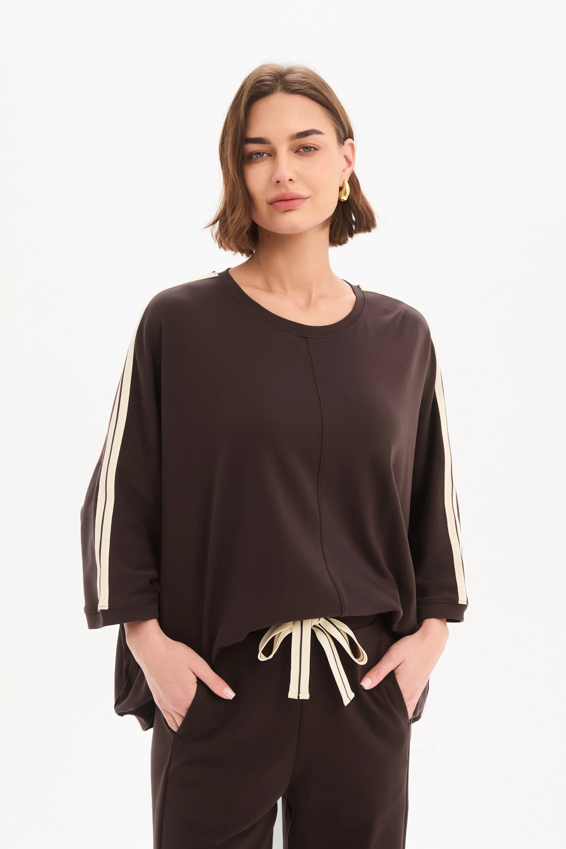 Woman wearing a brown outfit with white stripes on a white background