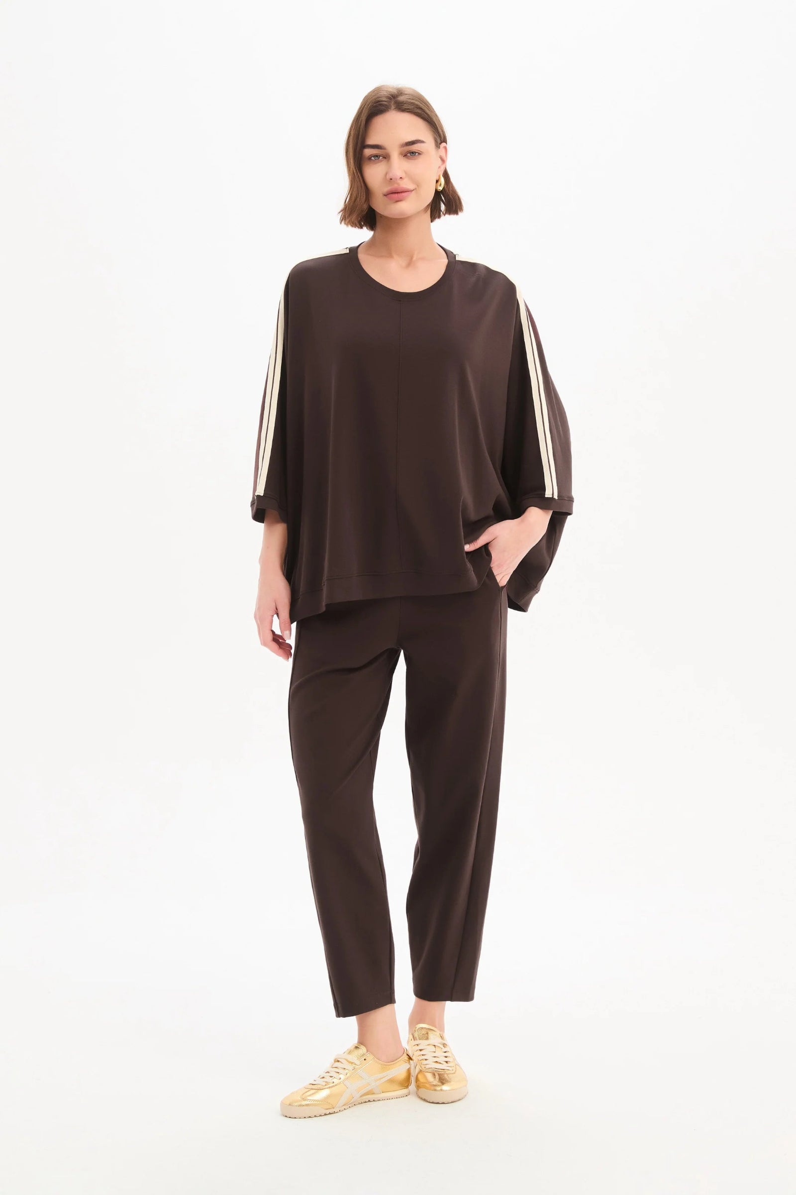 Woman wearing a brown outfit with white stripes on a white background