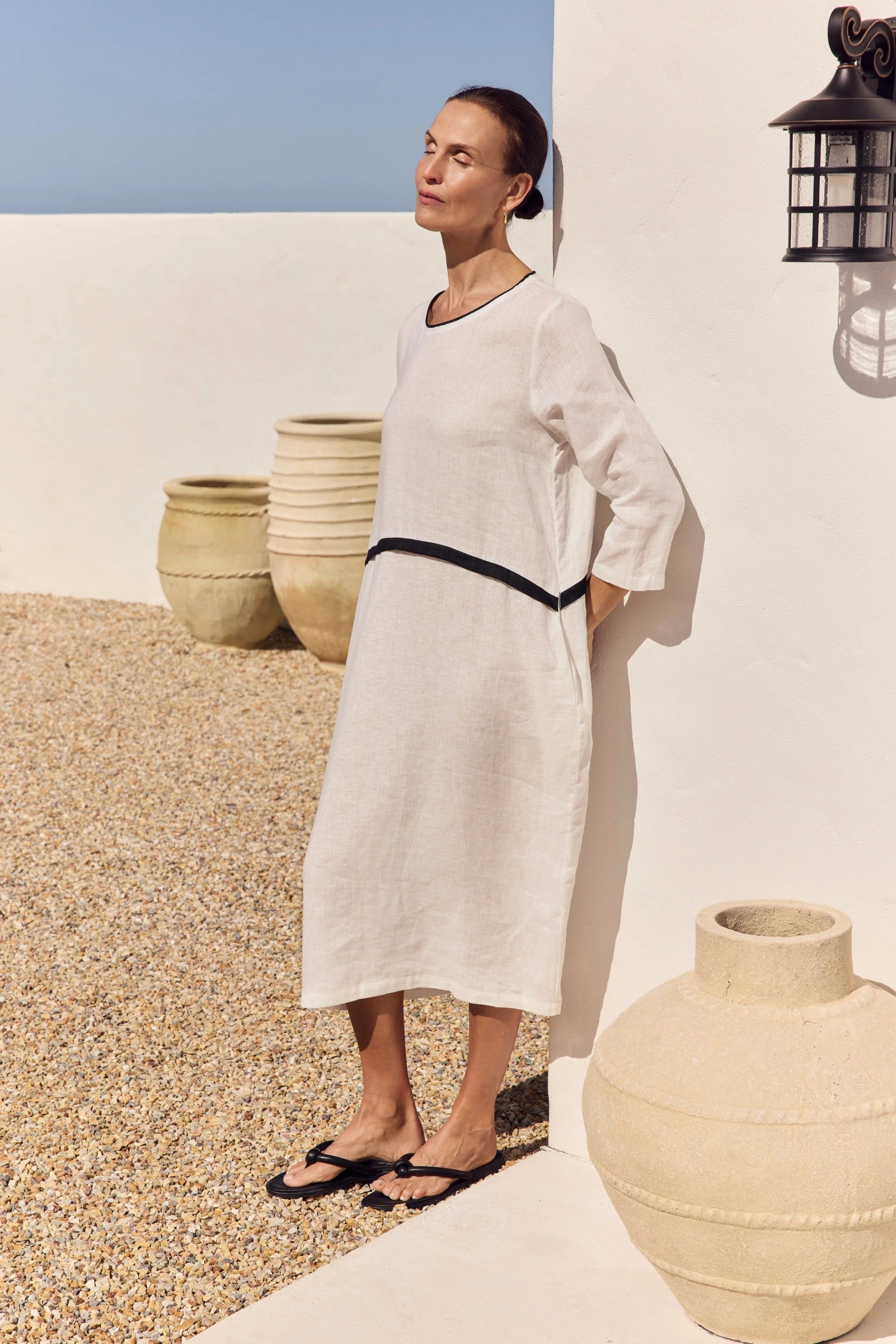 model wearing white dress with black detailing outdoors