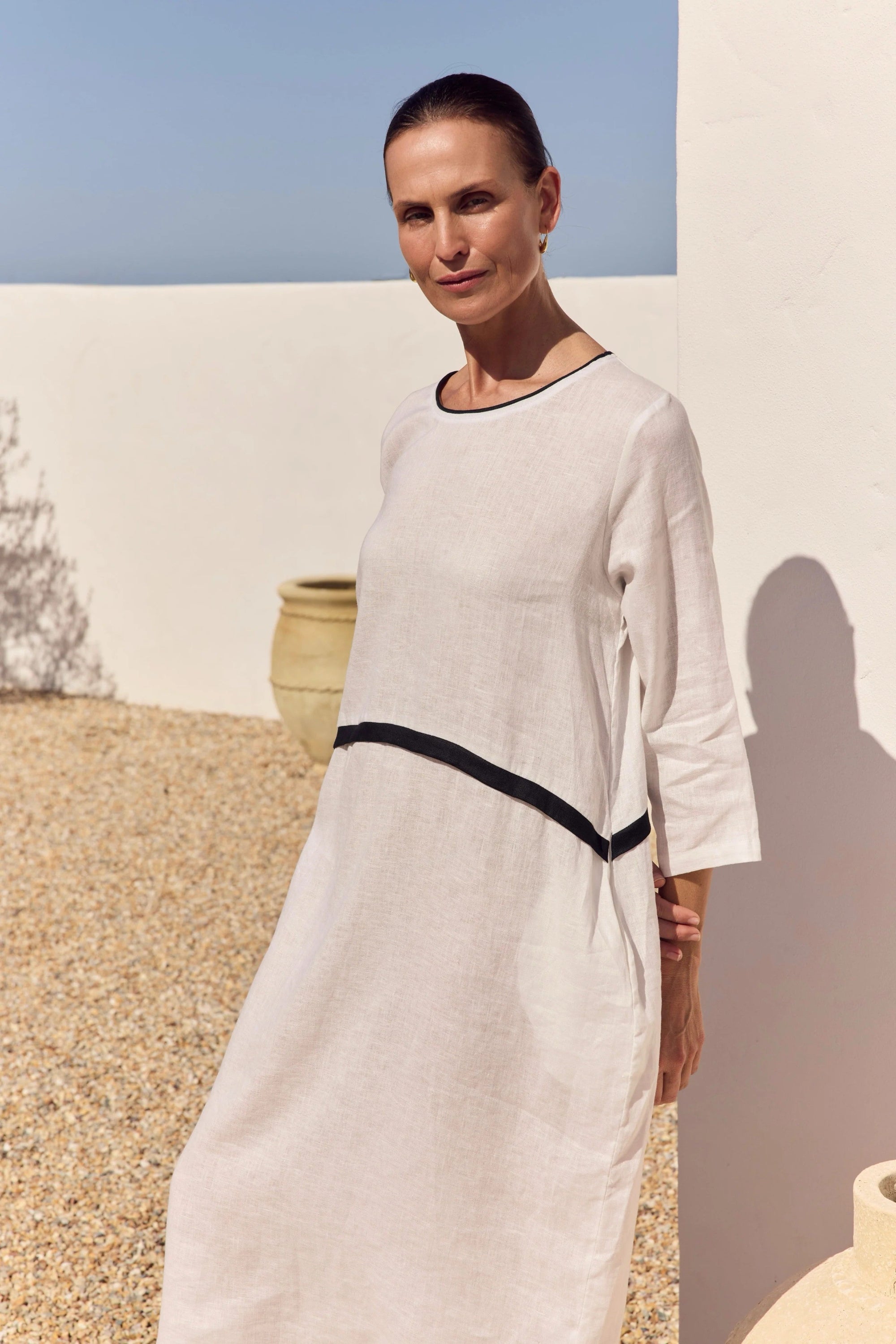 model wearing white dress with black detailing outdoors