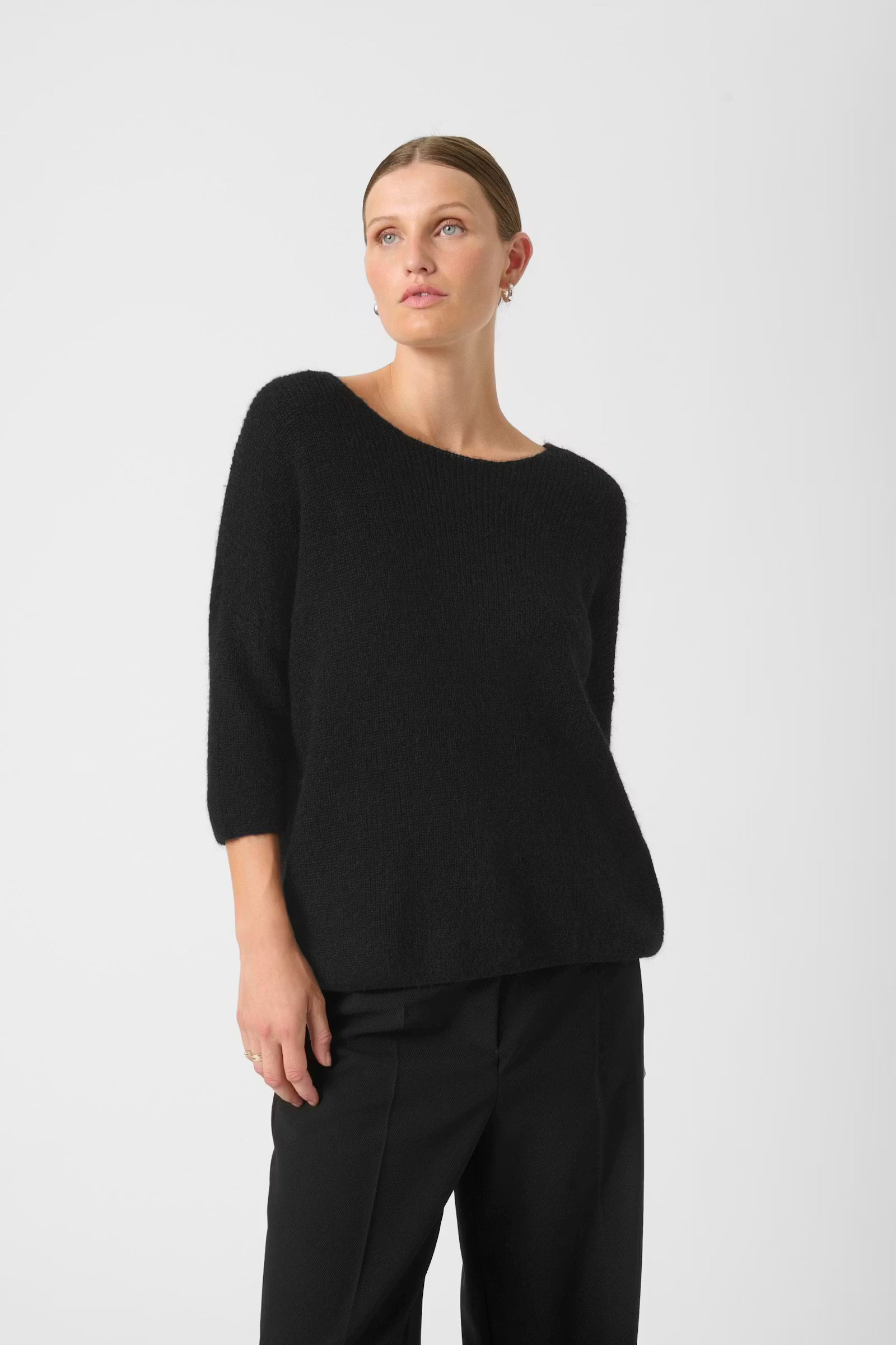 Woman wearing a black top and pants on a white background