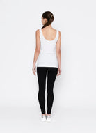 Person wearing a white tank top and black leggings on a white background