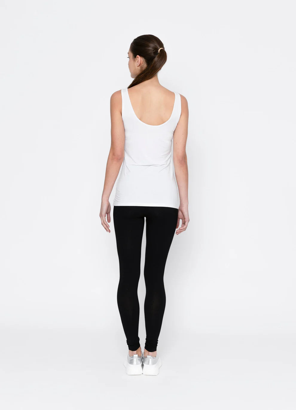 Person wearing a white tank top and black leggings on a white background