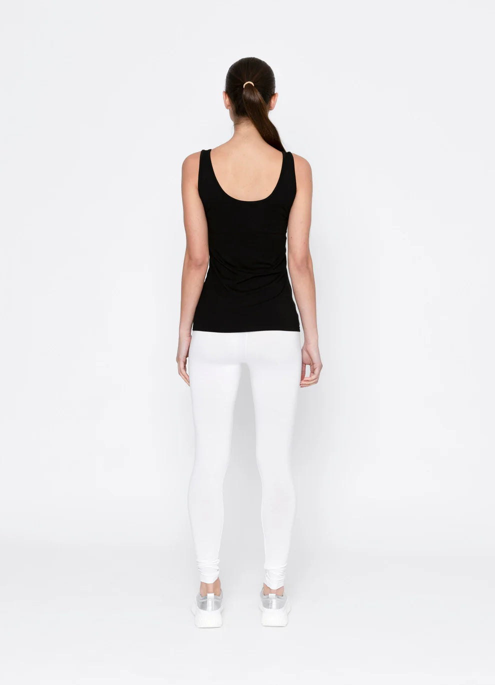 Person wearing a black tank top and white pants on a white background