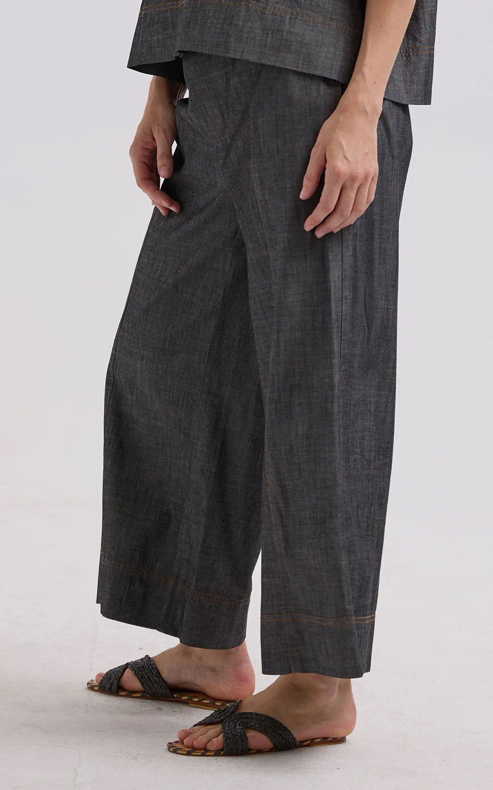 Person wearing dark gray wide-leg pants on a white background