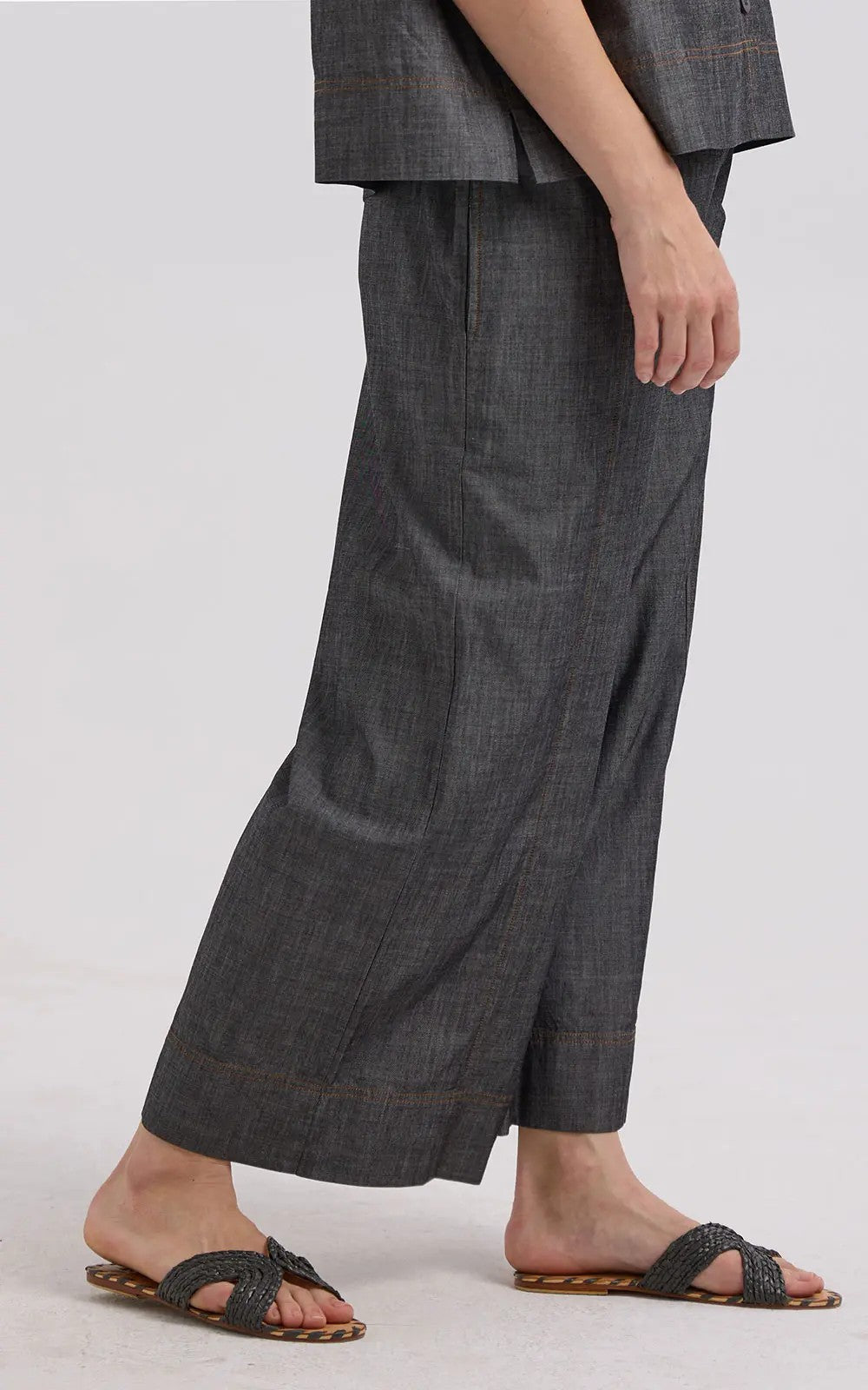 Person wearing dark gray wide-leg pants on a plain background